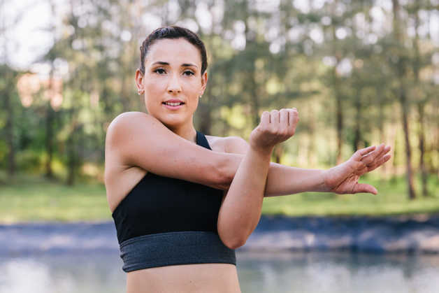 Alba doing shoulder stretch, woman, outside 